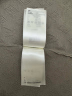Care label on light gray knit polo fabric with manufacturing info