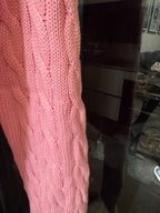 Pink cable-knit sleeve and side seam detail of cardigan sweater.