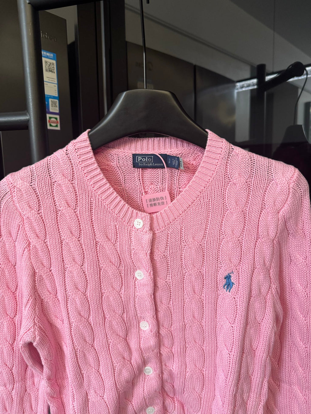 Pink cable-knit cardigan with V-neck, button front, and Polo logo patch at chest.