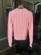 Pink cable-knit cardigan sweater, back view with ribbed hem and long sleeves.