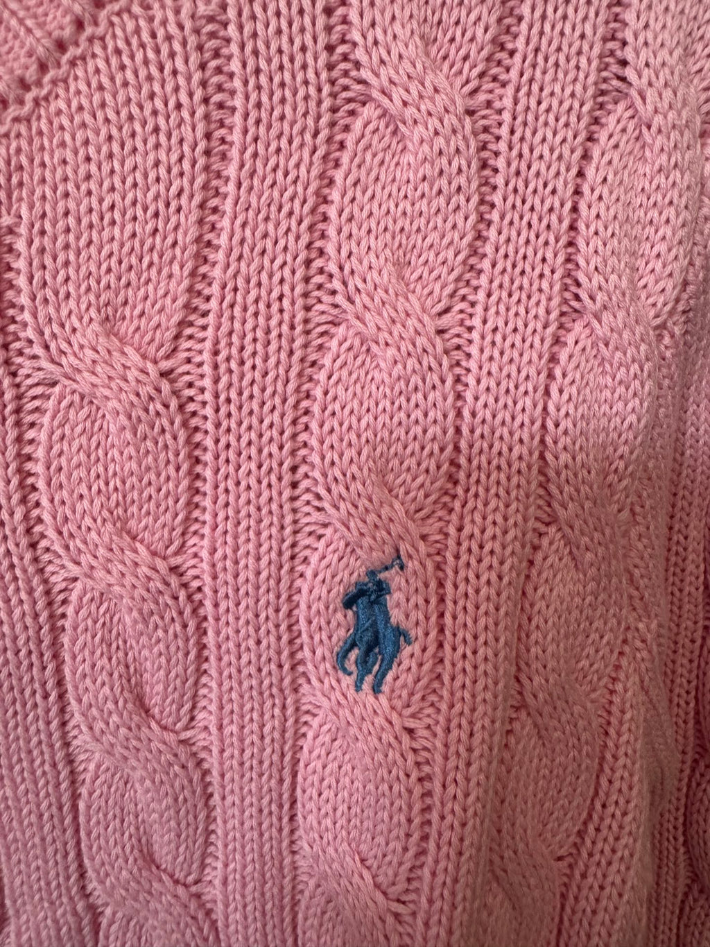Pink cable-knit sweater with small blue Polo logo on knit texture.