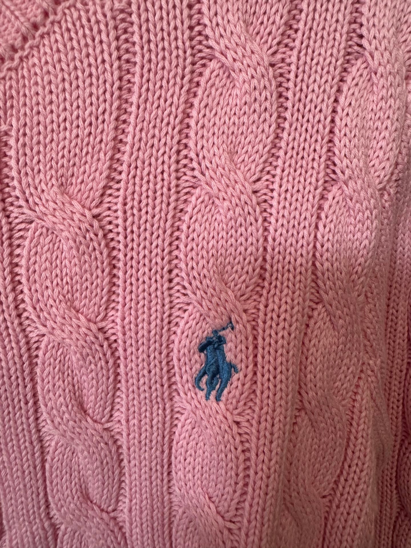 Pink cable-knit sweater with small blue Polo logo on knit texture.