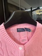 Pink cable-knit cardigan on hanger with Polo by Ralph Lauren neck label and buttons.