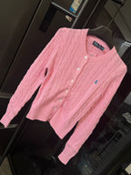 Pink cable-knit cardigan sweater with Polo logo and button placket, angled view.