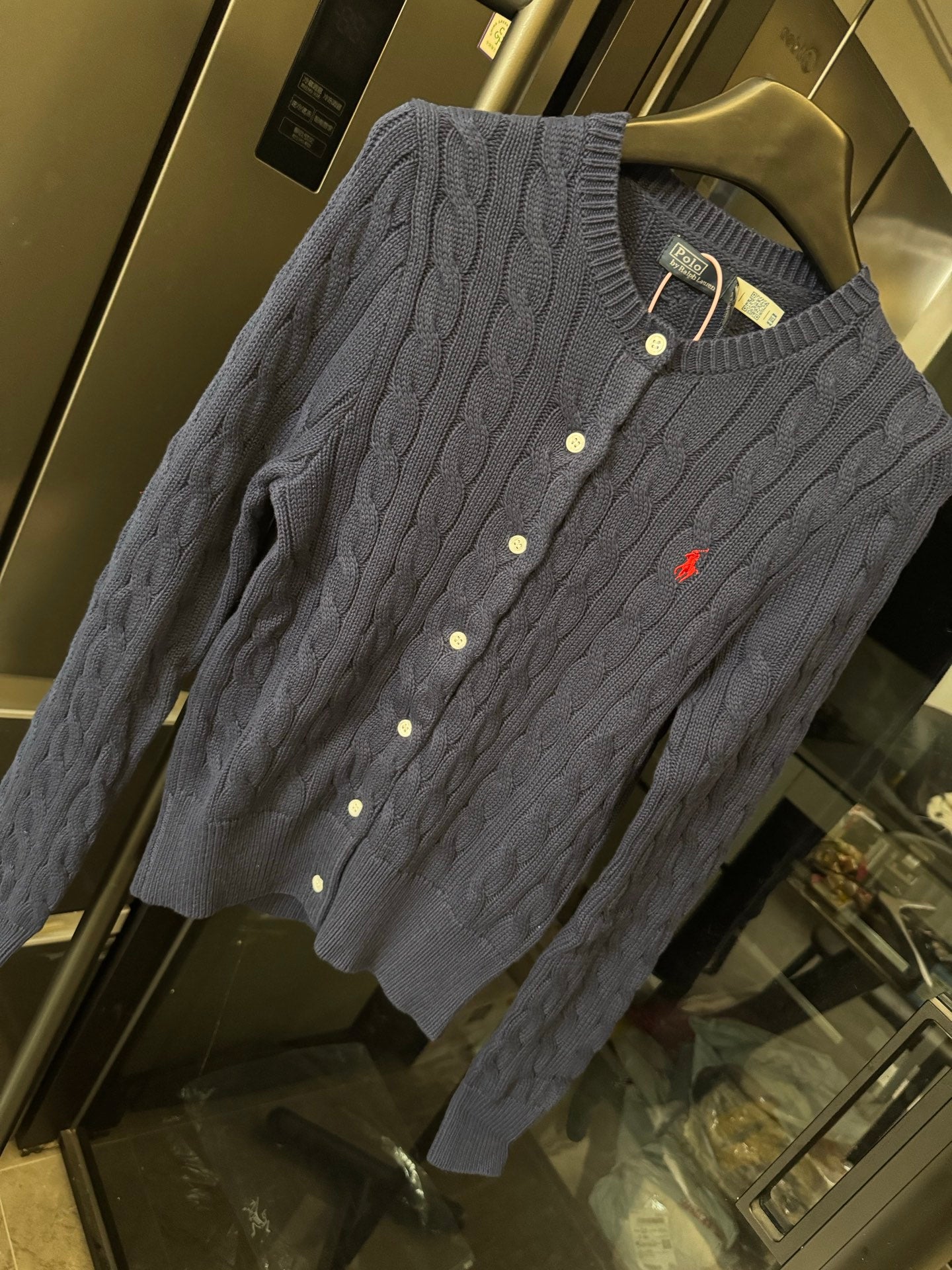 Dark gray cable-knit cardigan with button front, red polo logo, ribbed collar