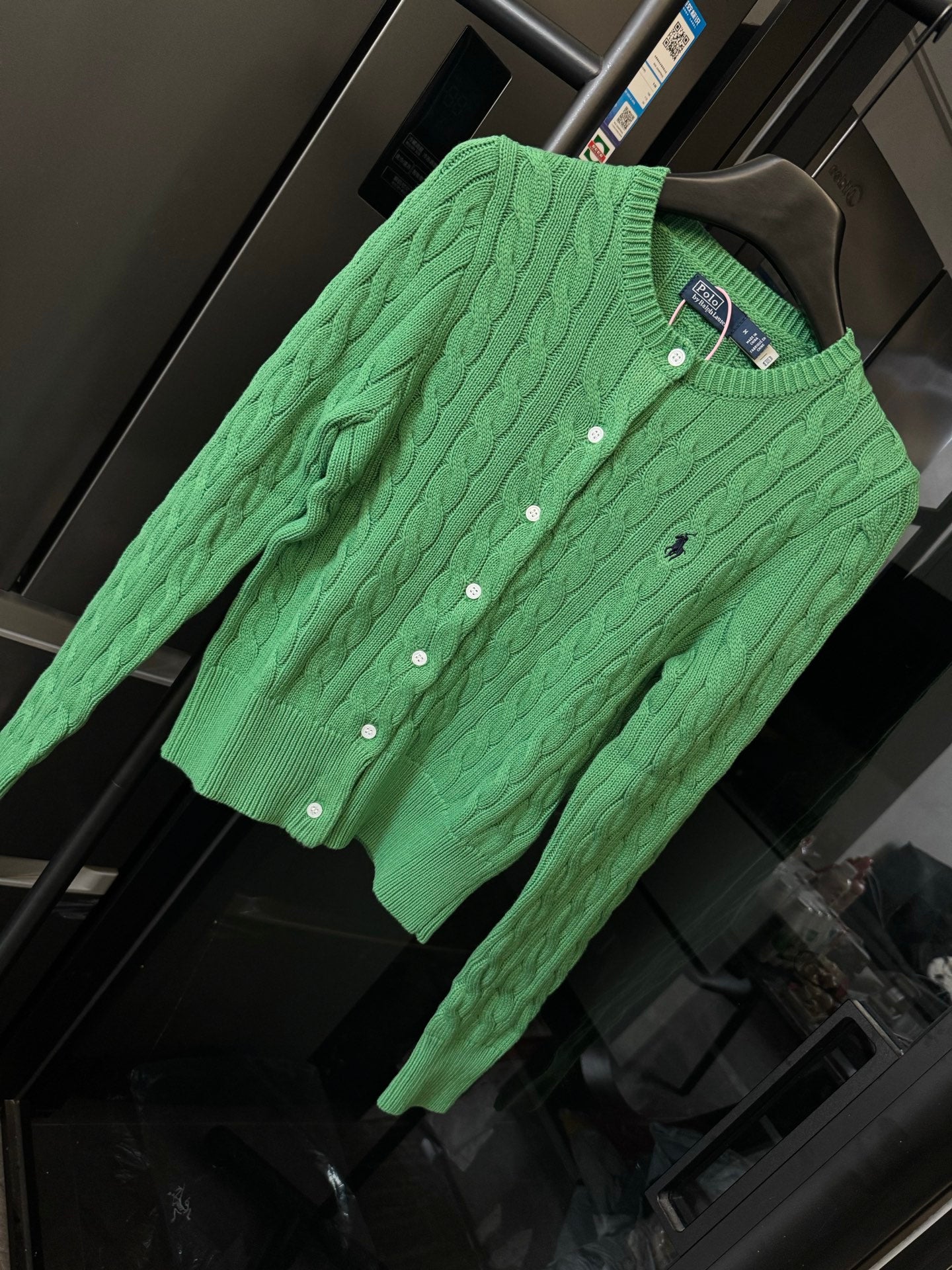 Green cable-knit cardigan with Polo logo and button placket, angled view