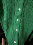 Green cable-knit cardigan with four white buttons on front