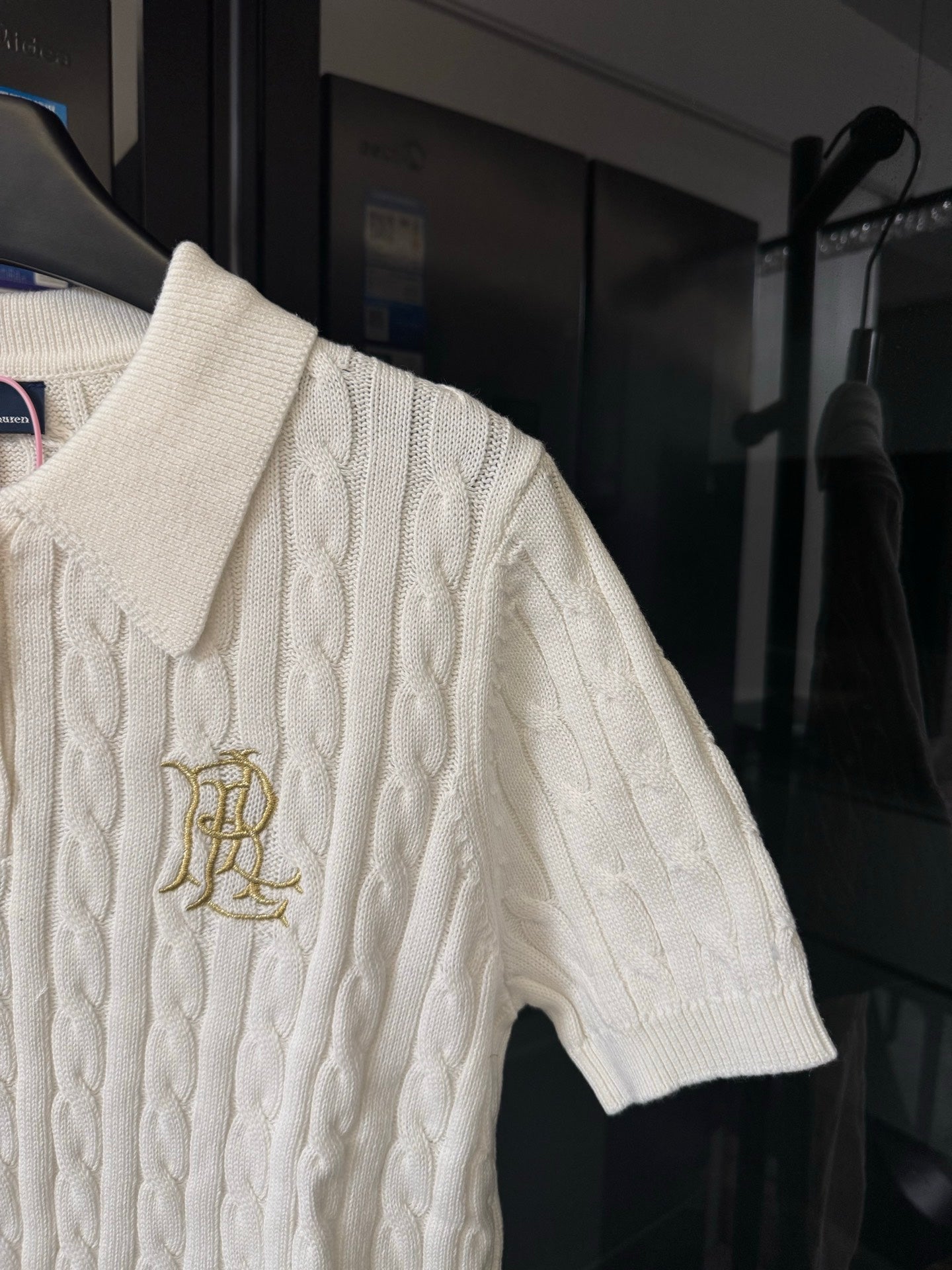 Ivory cable-knit polo shirt sleeve with embroidered gold chest logo