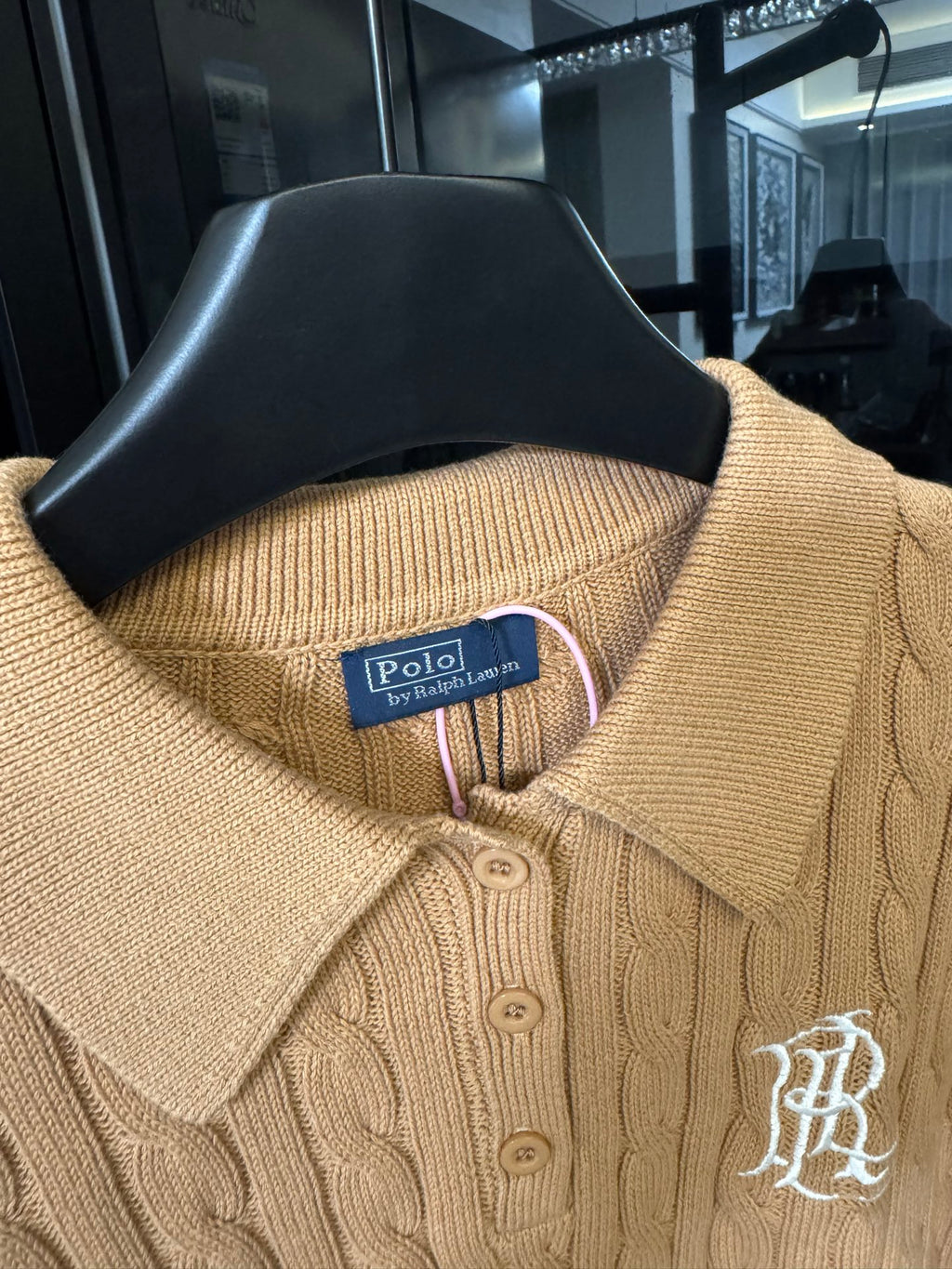 Ralph Lauren cable-knit polo shirt in beige, close-up of ribbed collar and button placket.