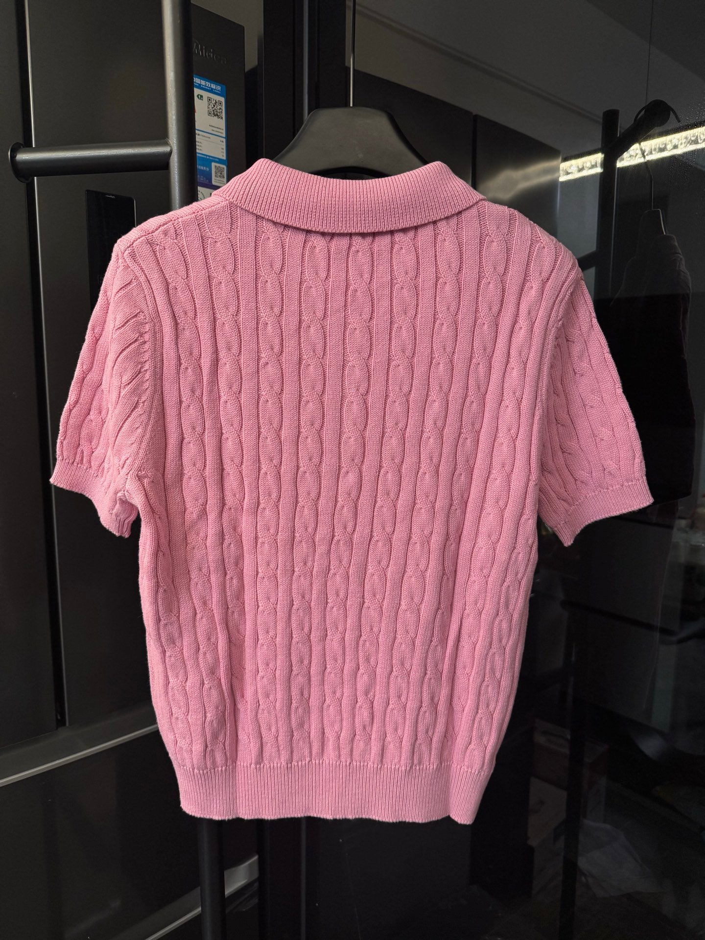 Back view of pink cable-knit polo shirt with ribbed collar and hem