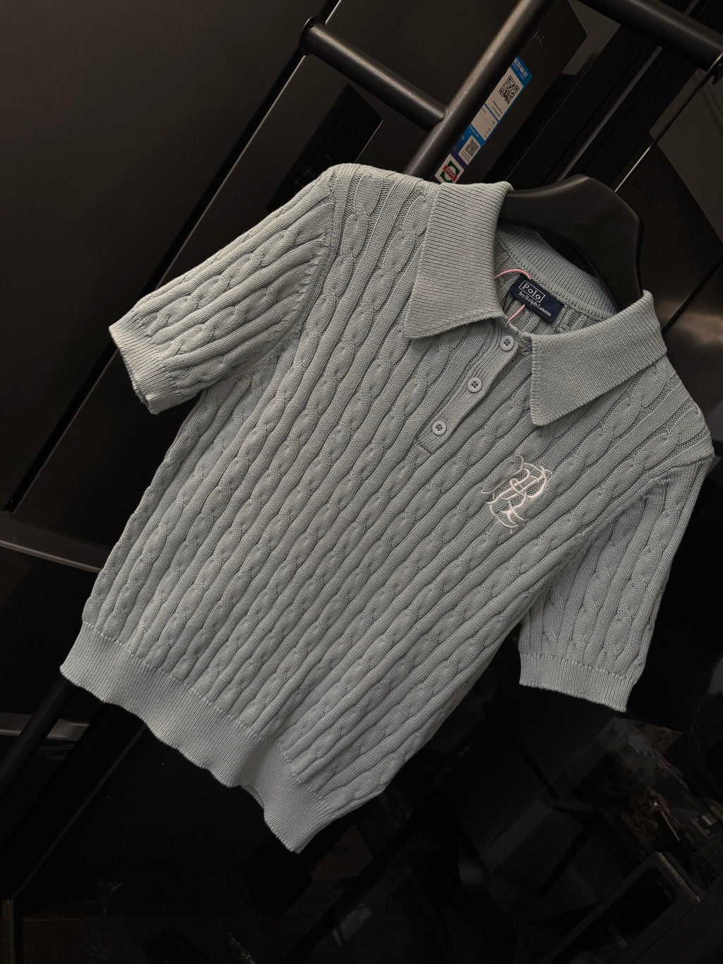 Gray cable-knit polo sweater with ribbed collar, three buttons, and chest logo