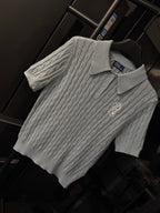 Gray cable-knit polo sweater with ribbed collar, three buttons, and chest logo