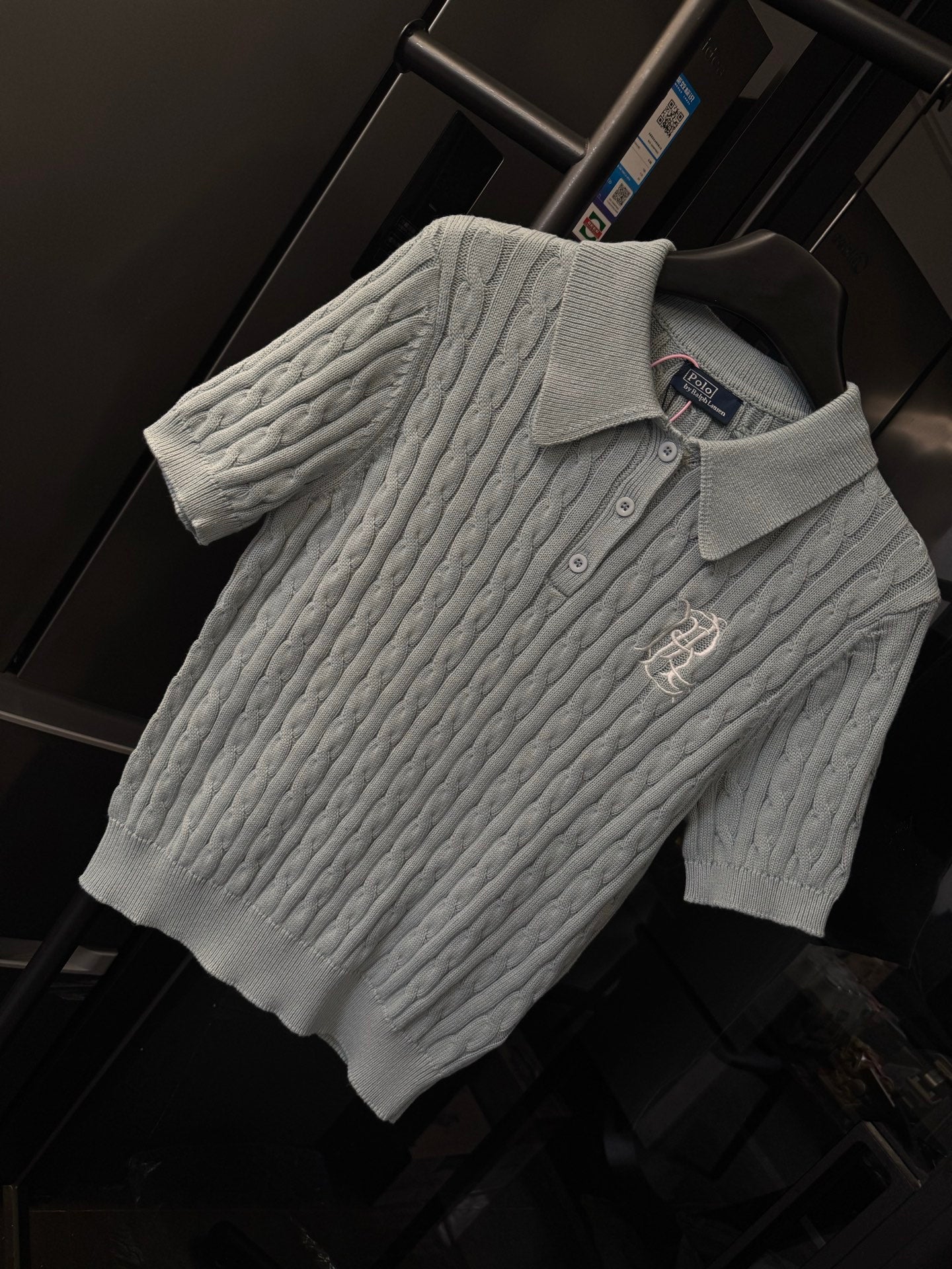 Gray cable-knit polo sweater with ribbed collar, three buttons, and chest logo