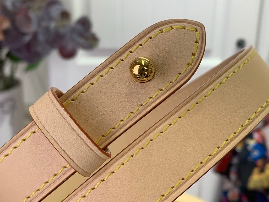 Beige leather bag flap with gold clasp and green stitching
