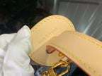 Louis Vuitton leather key holder with gold ring on tan backing, on blue bag