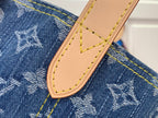 Tan leather strap tab with stitched edge on blue denim-style monogram fabric