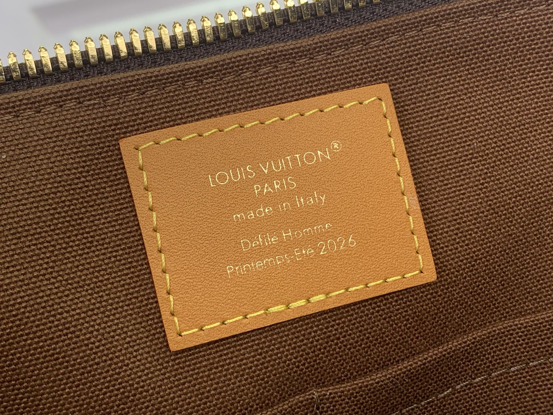 Louis Vuitton monogram bag interior leather label with stamped text and stitching.