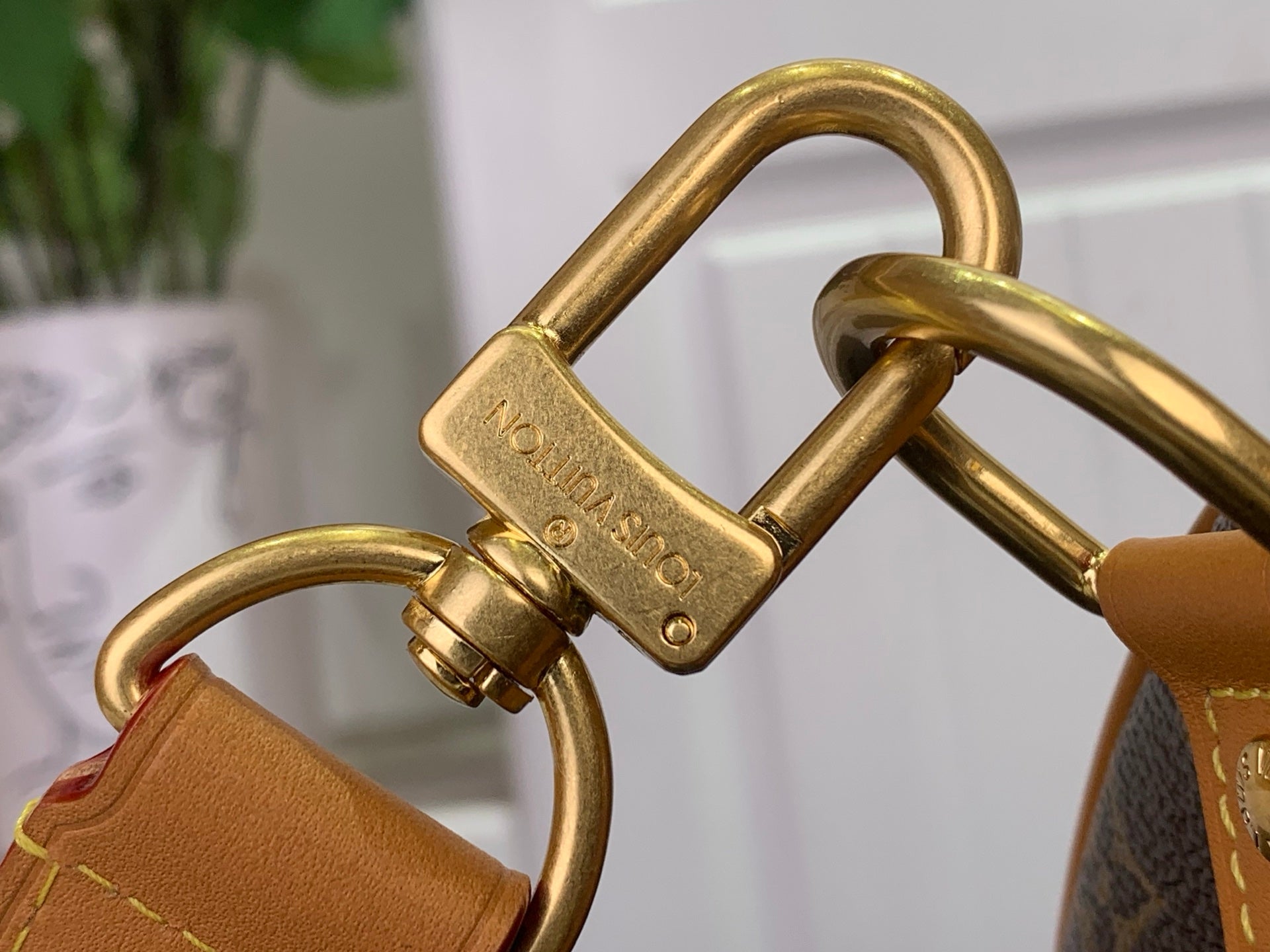 Louis Vuitton gold-tone D-ring and buckle hardware on tan leather strap.