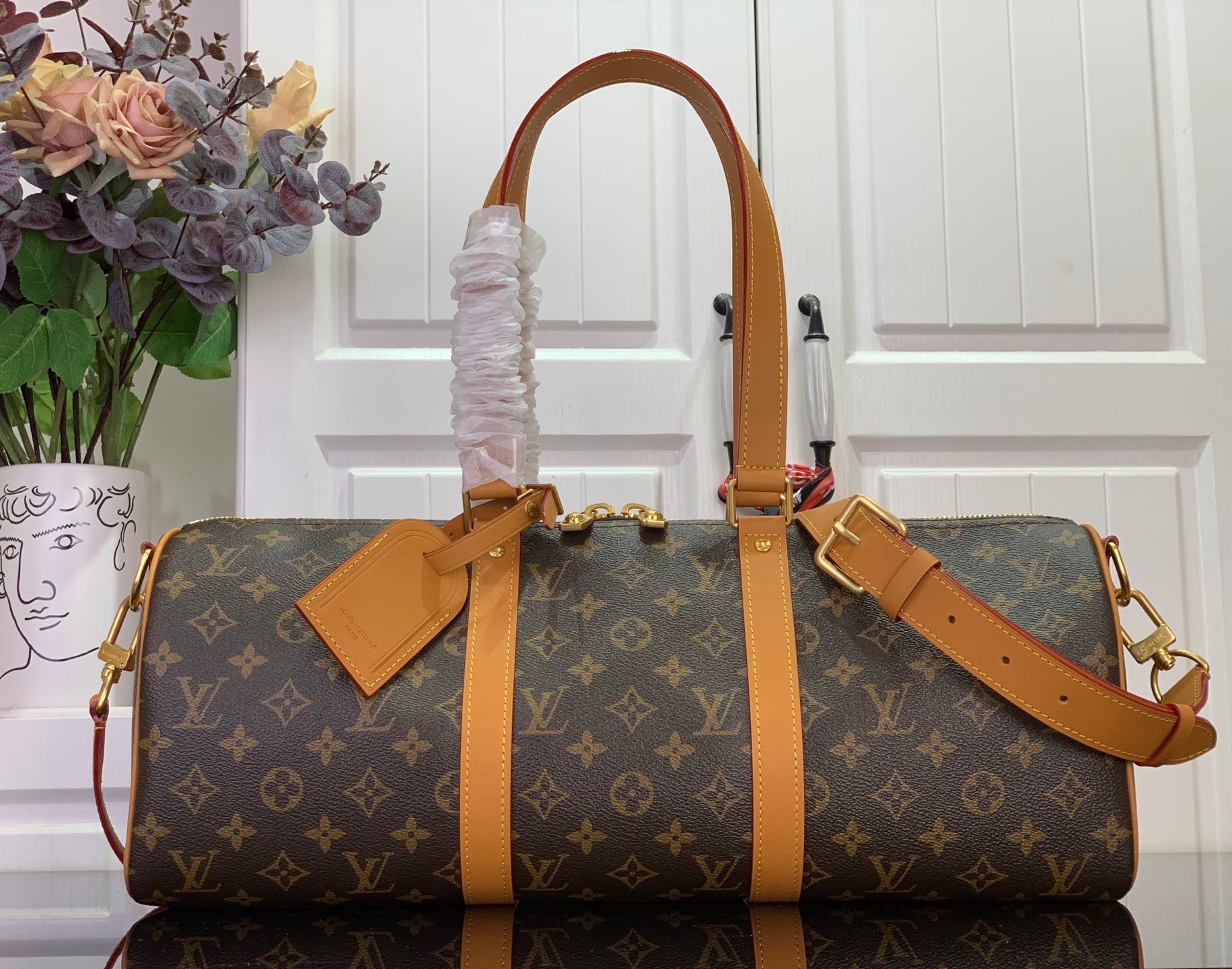 Louis Vuitton monogram duffel bag with tan leather trim and top handles, side straps.