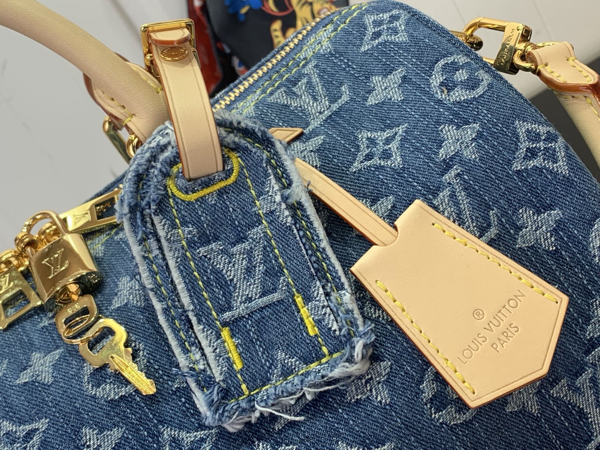 Louis Vuitton blue monogram handbag detail with denim-like texture and tan leather tag