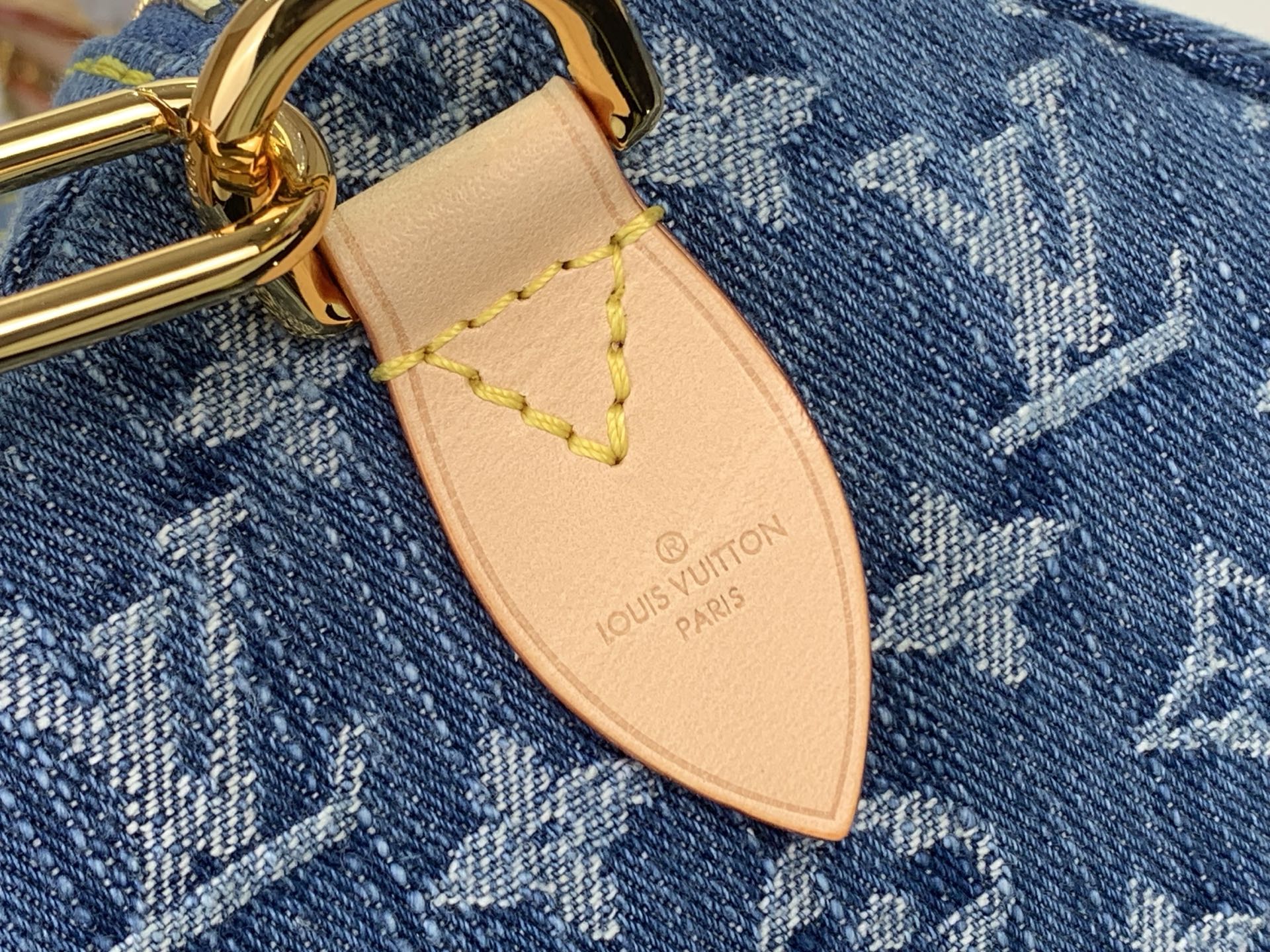 Louis Vuitton leather bag charm with gold ring and brand logo on denim