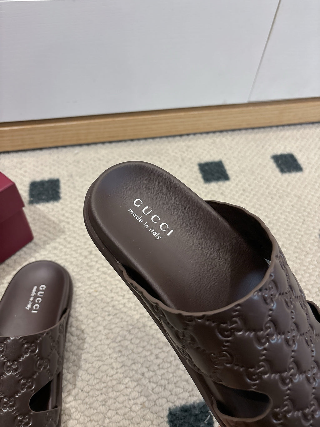 Gucci dark brown embossed slide sandal with 'Gucci' text on footbed