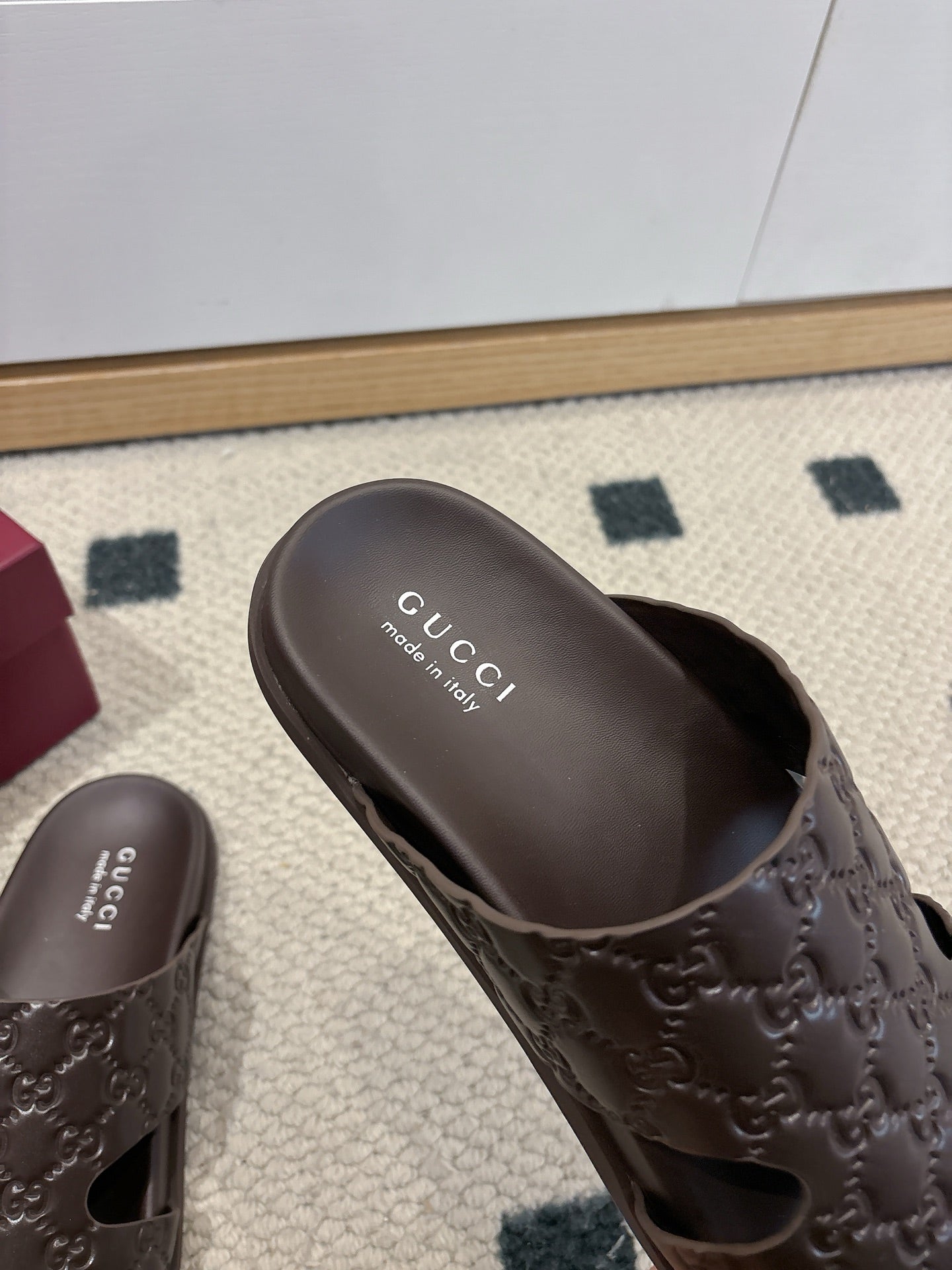 Gucci dark brown embossed slide sandal with 'Gucci' text on footbed