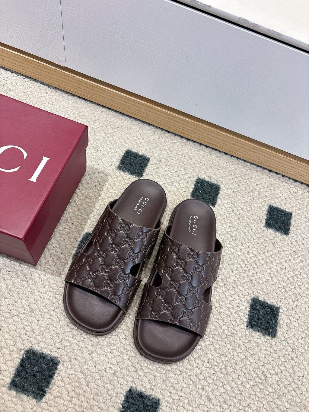 Gucci dark brown leather slide sandals with open toe and embossed logo pattern