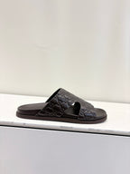 Gucci dark brown embossed slide sandal on display, open toe and logo strap