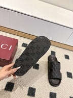 Gucci black slide sandals showing textured monogram footbed