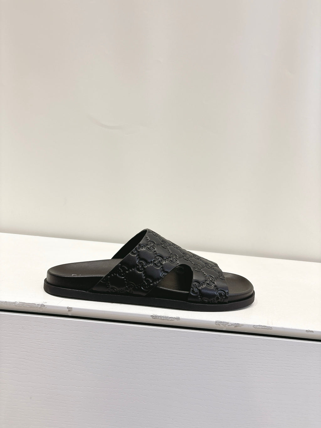 Gucci black slide sandal with embossed monogram strap