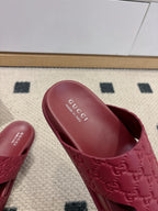 Close-up of burgundy Gucci slide sandal with embossed GG upper and branded insole