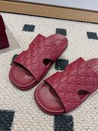 Two burgundy Gucci GG slide sandals with open toe and cushioned molded footbed