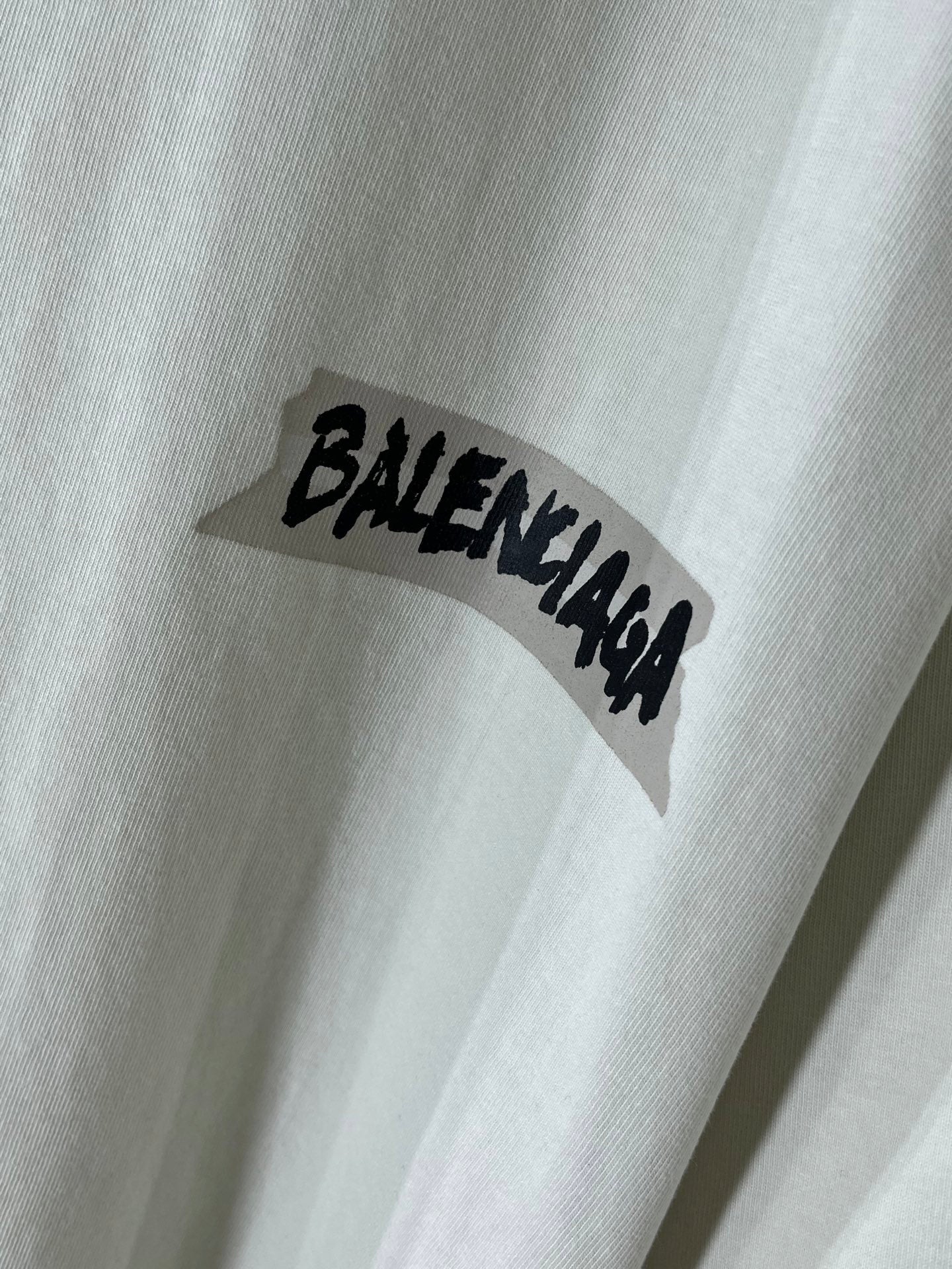 White Balenciaga T-shirt sleeve with black BALENCIAGA logo text