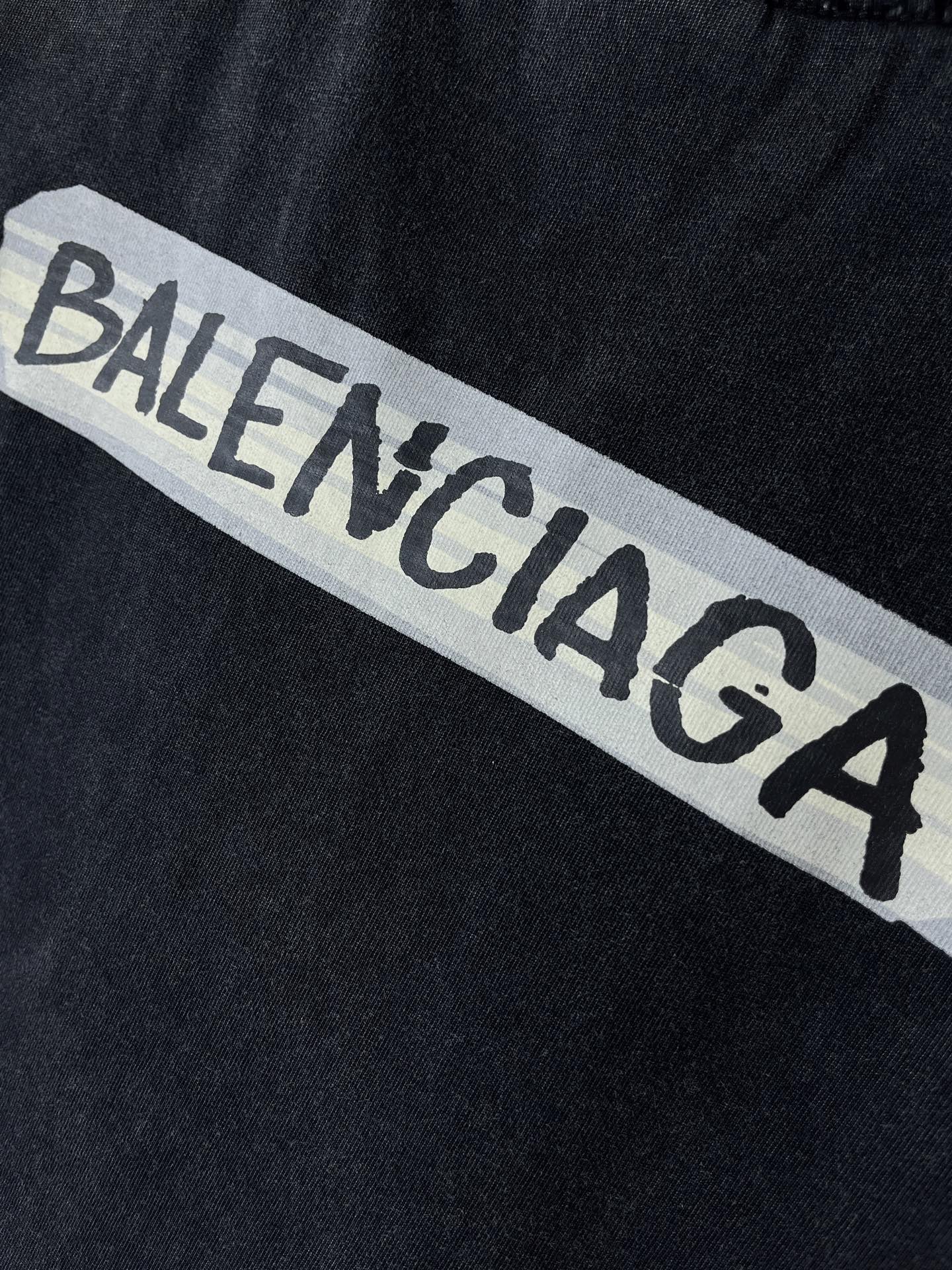 Close-up of BALENCIAGA logo print on dark navy T-shirt fabric