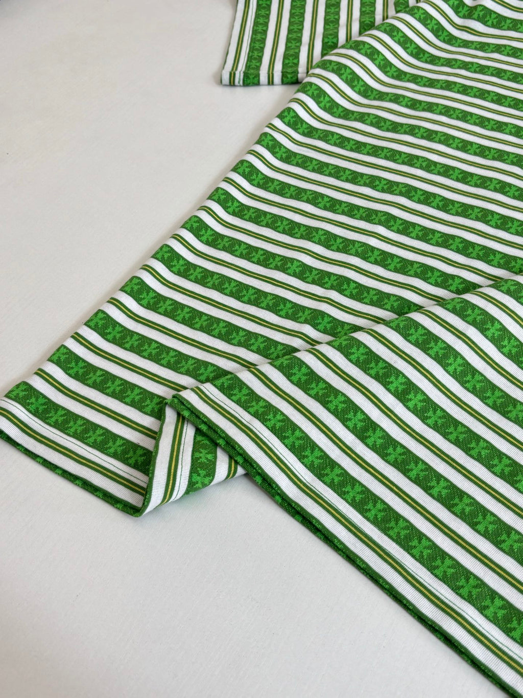 Folded green striped short-sleeve T-shirt with crew neck and striped fabric texture
