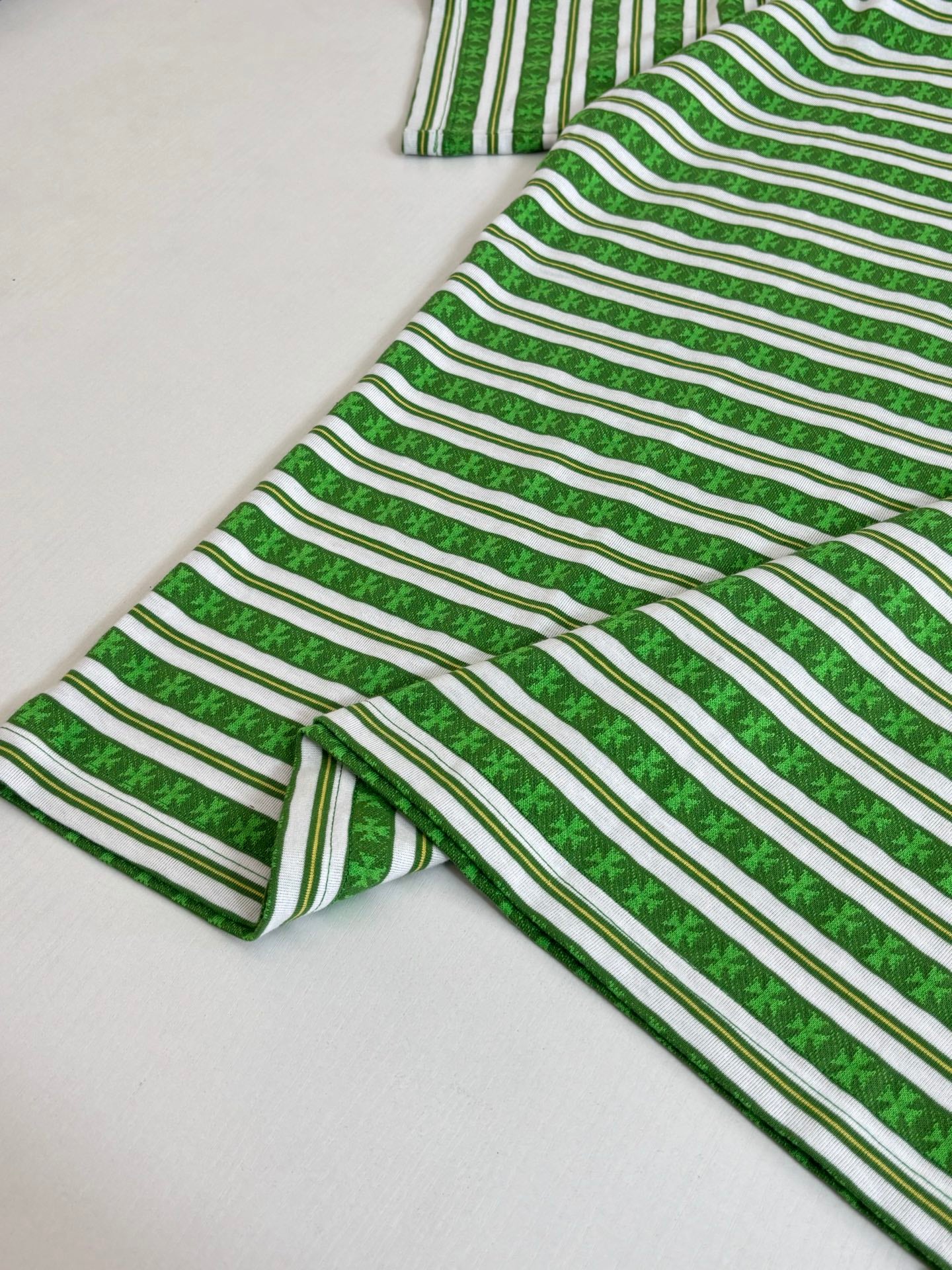 Folded green striped short-sleeve T-shirt with crew neck and striped fabric texture