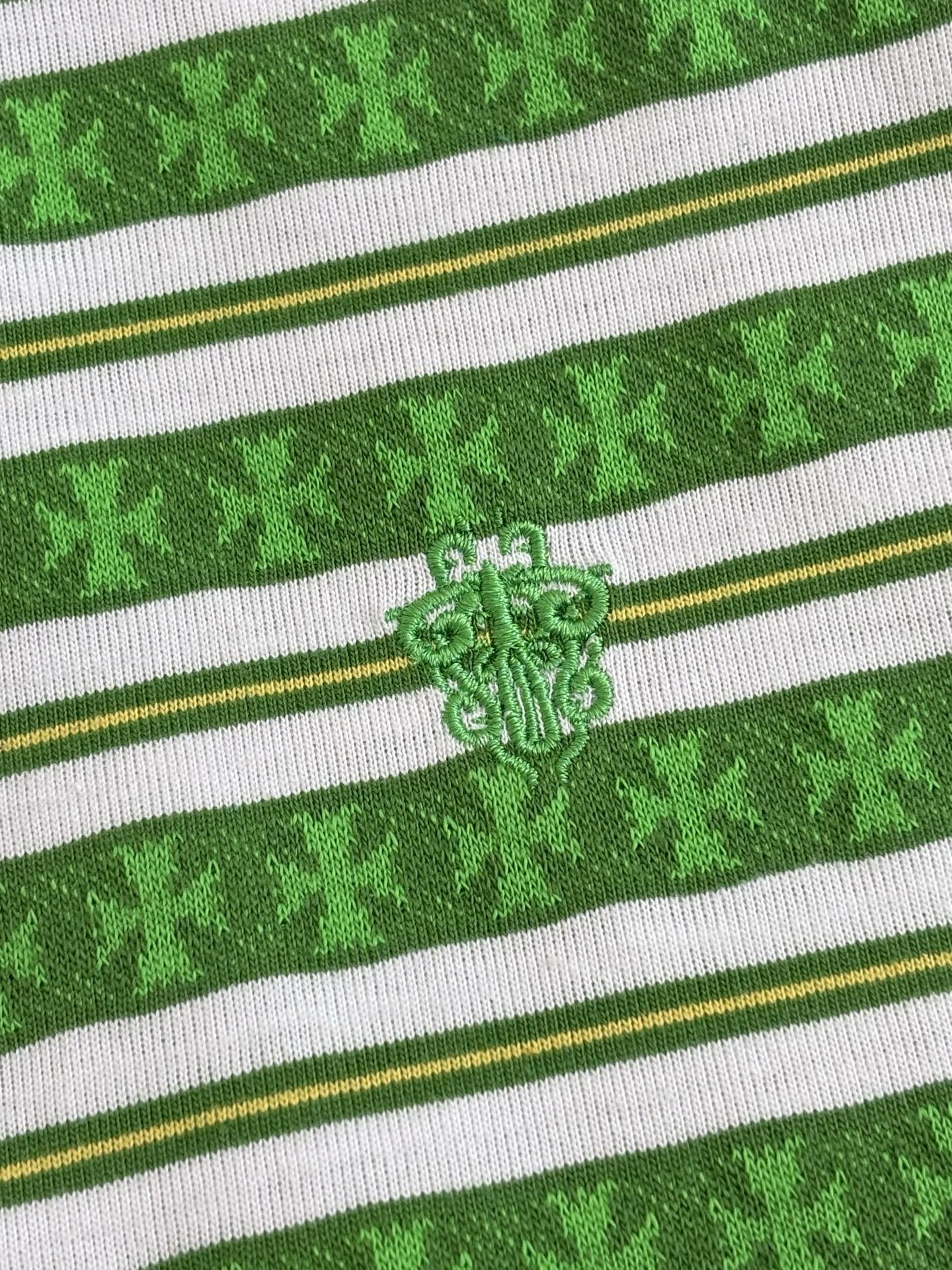 Close-up of green striped knit T-shirt with embroidered crest logo