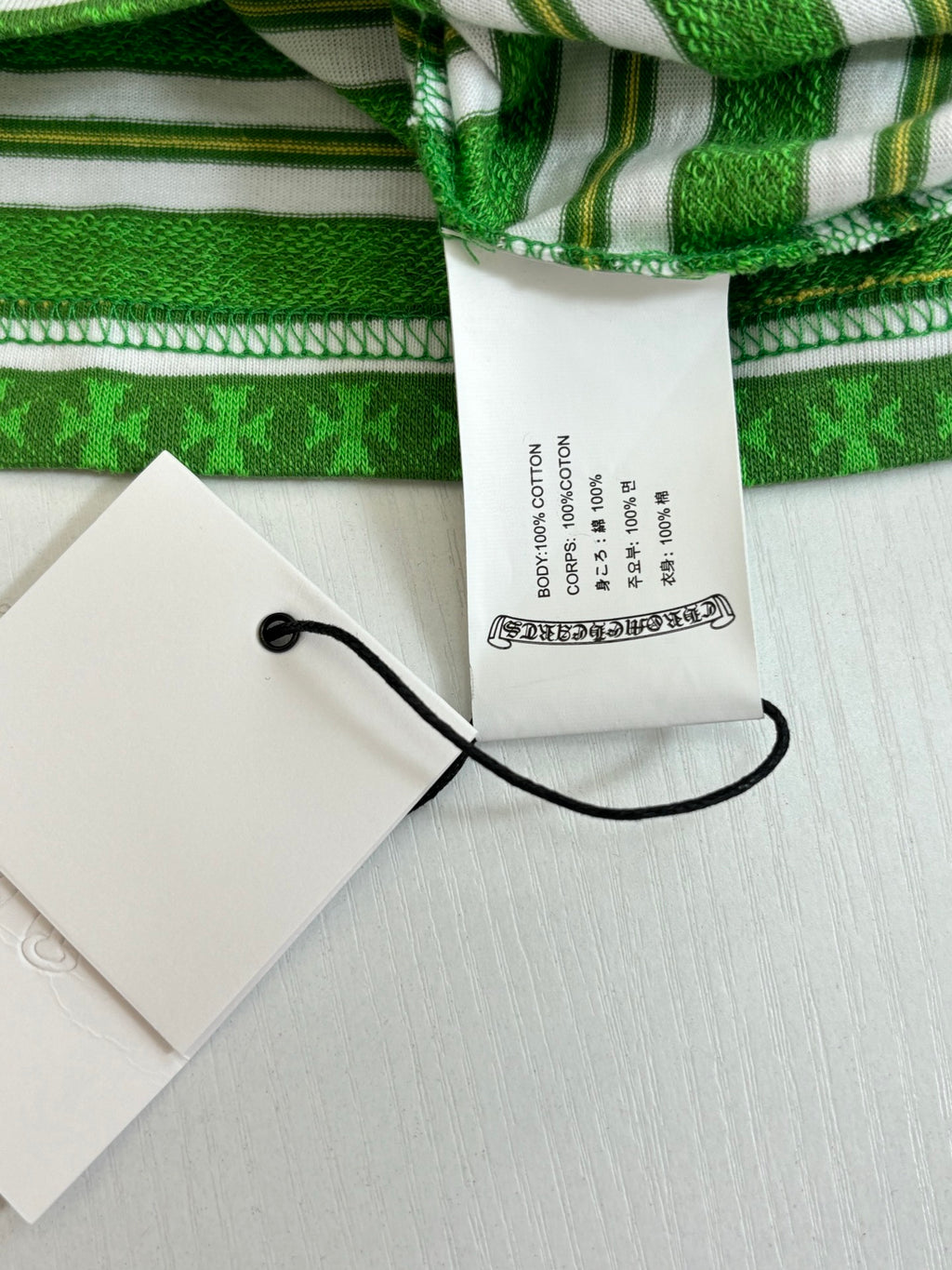 Green striped T-shirt with white neck label and black string attached to tag