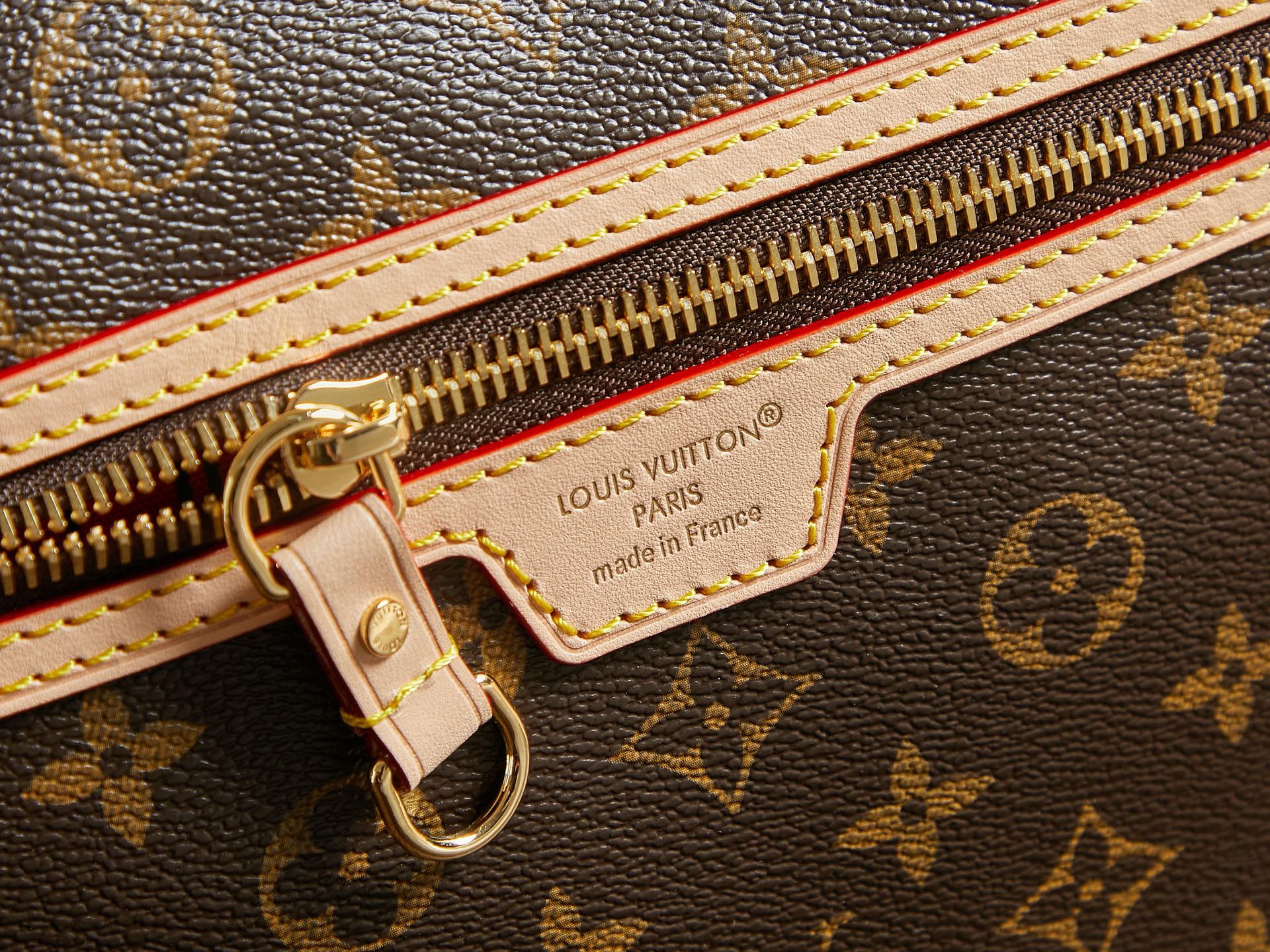Louis Vuitton monogram bag zipper close-up with gold hardware and label patch