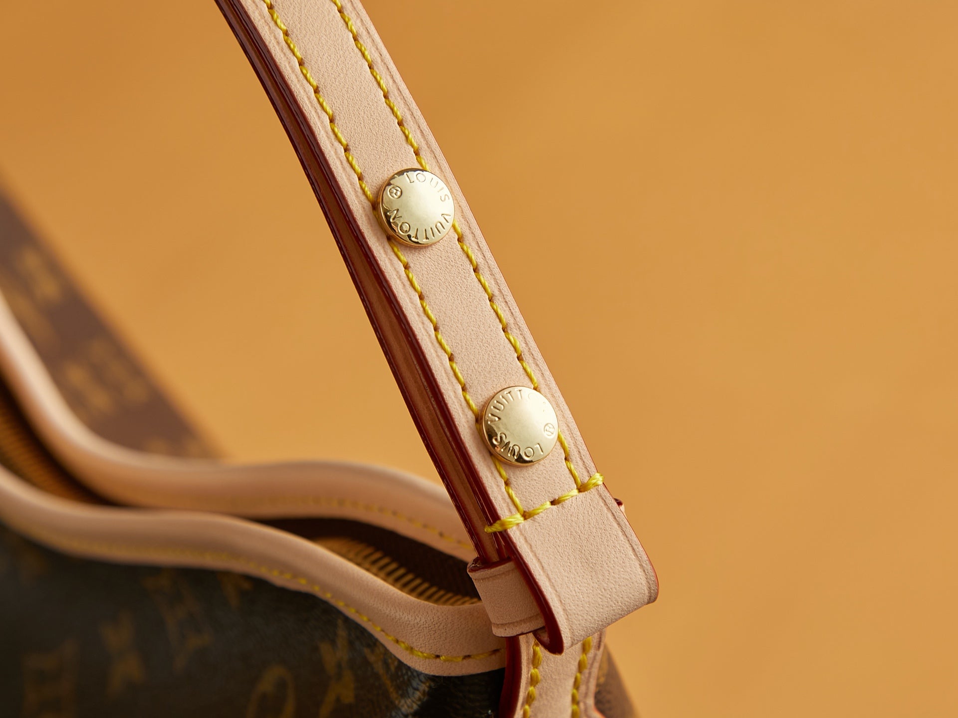 Louis Vuitton monogram bag strap end with gold snap hardware and red stitch edging