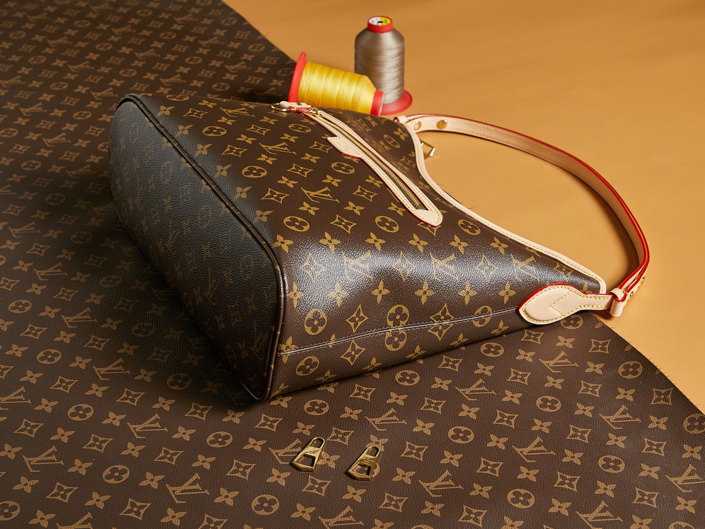 Louis Vuitton monogram bag with red handle trim and top zipper pull, side profile