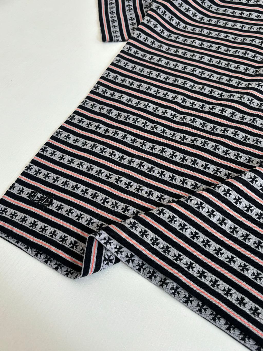 Folded T-shirt with black, white, and red striped knit and repeating motif row
