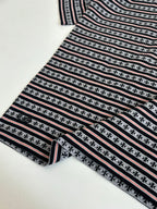 Folded T-shirt with black, white, and red striped knit and repeating motif row