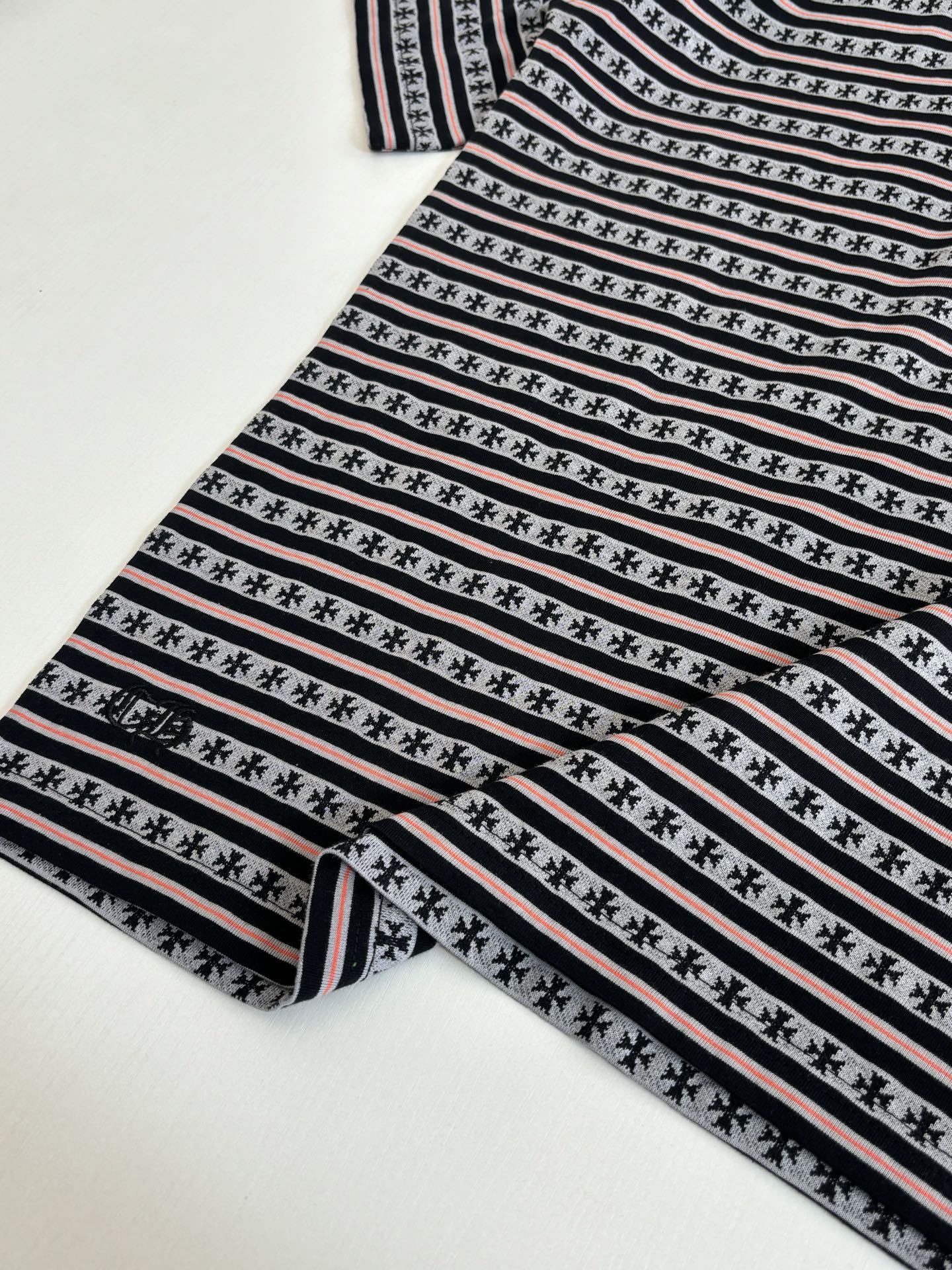 Folded T-shirt with black, white, and red striped knit and repeating motif row
