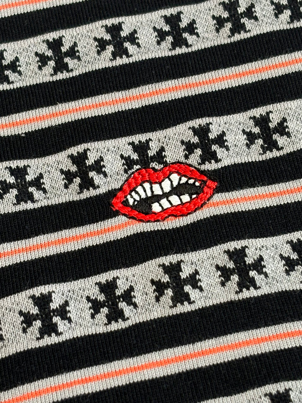 Close-up of striped knit T-shirt with red lip graphic and small dark motifs