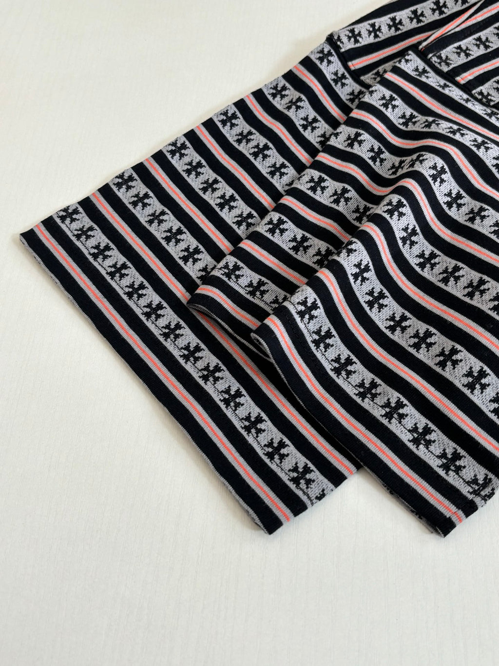 Laid-flat striped T-shirt with black-and-white bands and thin red stripes