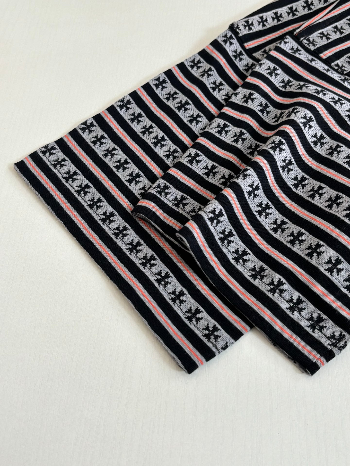 Laid-flat striped T-shirt with black-and-white bands and thin red stripes