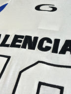 Balenciaga logo graphic on white jersey front, close-up of black lettering and blue stripe