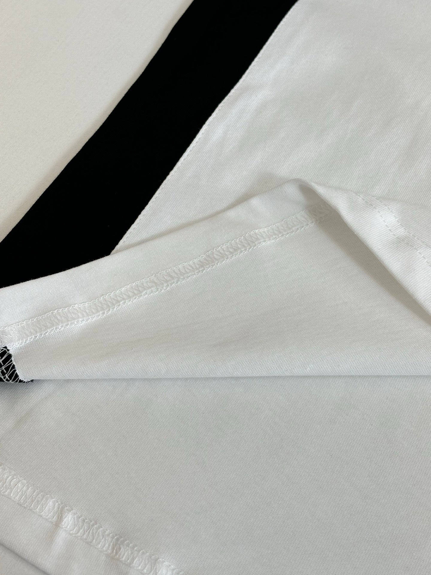 Balenciaga jersey hem close-up with white fabric and black side stripe